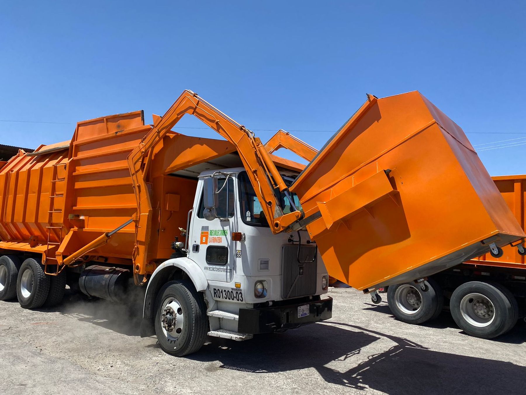 Camión de carga frontal de Recolectores La Frontera levantando un contenedor naranja en Ciudad Juárez