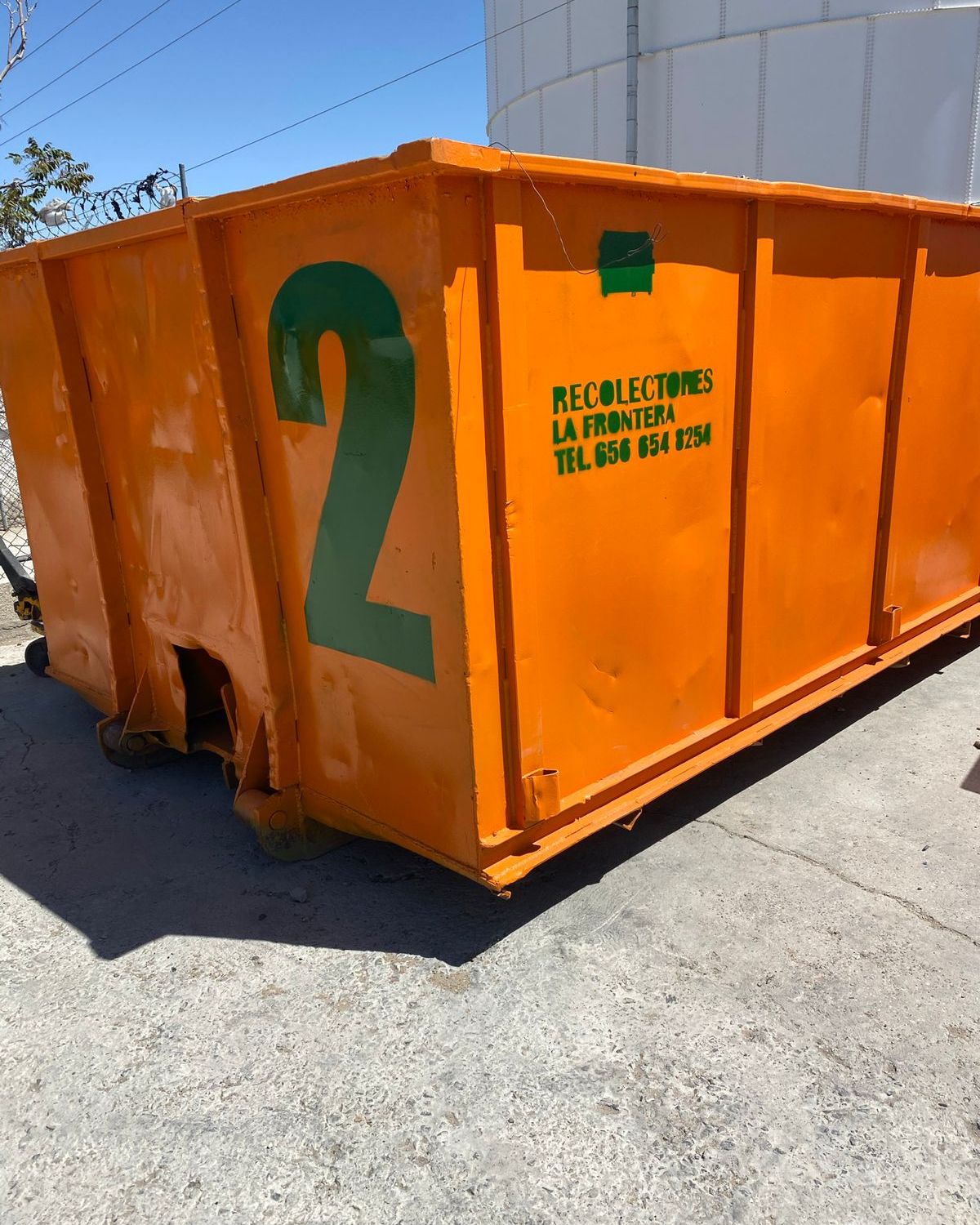Caja roll-off naranja de Recolectores La Frontera colocada en piso